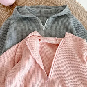 Infant waffle knit hooded zip-up jacket detail, cozy autumn baby outerwear piece.