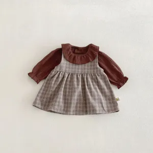 Completo primaverile da bambina con blusa con colletto a bambola e vestito a quadri grigio.