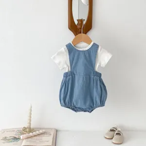 Detailed view of the baby denim romper and white tee set hanging cleanly against a neutral wall.