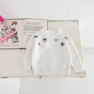 Baby white knit cardigan with embroidered flowers and dot texture, infant sweater detail view.