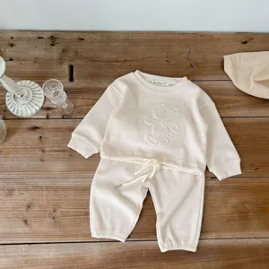 Detail shot of infant waffle knit sweater set in beige, featuring cute bear embossing and collar label.