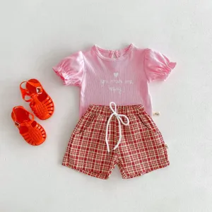 Tenue d'été pour bébé avec t-shirt à manches courtes, short à carreaux et sandales.