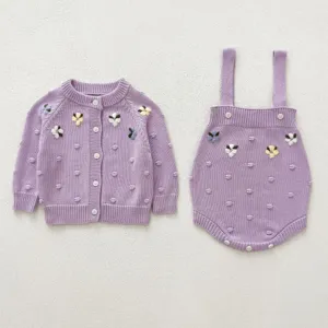 Detail shot of baby knit cardigan and strap romper set with cute embroidered flowers.