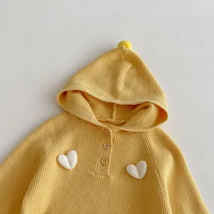 Detailed view of a yellow knit hooded children sweater featuring 3D white hearts and buttons.