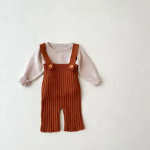 Gedetailleerd overzicht van de baby gebreide trui en bruine tuinbroek set, zachte stof.