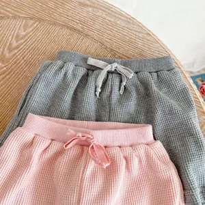 Close-up detail of infant waffle knit pants in grey and pink with soft drawstring waist.