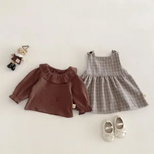 Completo primaverile per bambina con camicetta marrone e abito scamiciato a quadri.