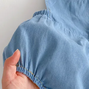 Detail of soft infant denim clothing showing elastic puff sleeve texture and light blue fabric.