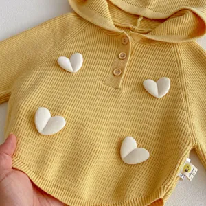 Close-up detail of yellow knit baby hoodie featuring cute 3D white heart appliqués and buttons.
