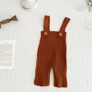 Detail gebreide baby bretels broek in bruin, zachte geribbelde stof met schattige houten knopen.