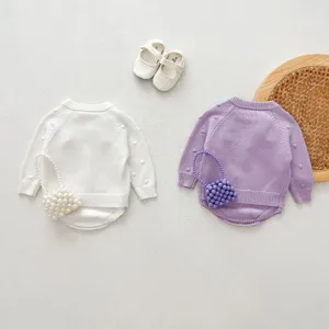Infant knitted sweater set detail view, featuring delicate textured knitwear and sweet baby shoes.