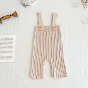 Gedetailleerd overzicht van gebreide baby tuinbroek, geribbelde textuur, knopen.