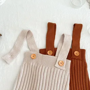 Gedetailleerd overzicht van gebreide baby bretbroek met houten knopen, zachte lente textuur.