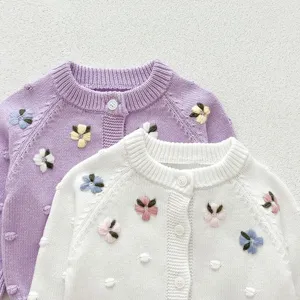 Detailed view of baby knit cardigan with floral embroidery and cute buttons close up shot