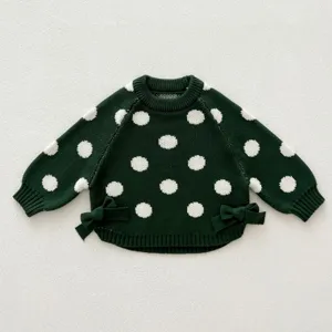 Detailed view of dark green knit toddler sweater with white polka dots and cute side bows.