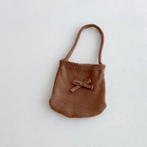 Primo piano dettaglio della borsa per bambini in maglia marrone con fiocco, morbida.