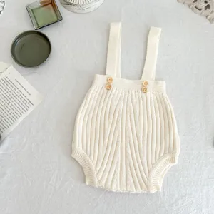 Baby Strick Rippen Träger Strampler Detail mit weicher Textur und süßen Holzknöpfen.