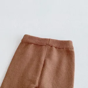 Dettaglio pantaloni neonato in maglia, vita elastica a costine, morbida consistenza autunno.