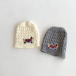 Nahaufnahme Details von weichen gestrickten Babymützen mit süßen Hundepatch-Mustern.