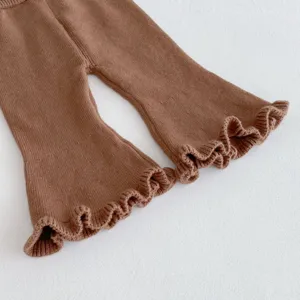 Dettaglio pantaloni a zampa in maglia marrone per neonata con simpatici polsini a volant.