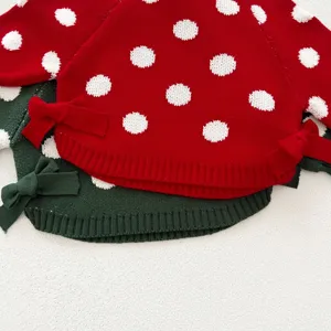 Close-up detail of knitted sweater fabric showcasing cute polka dots and side bow decoration.