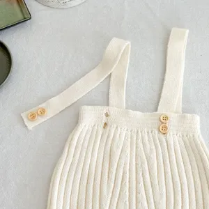 Säugling gerippter Strick Trägerstrampler Detail mit Textur und Holzknöpfen Verschluss.