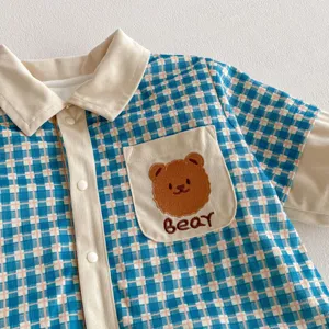 Detailed view of baby winter romper, blue plaid fabric, beige corduroy collar and bear pocket.