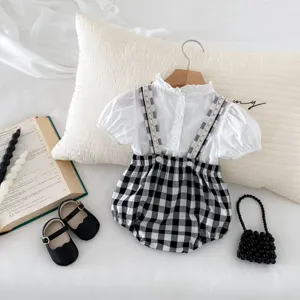 Detail view of baby girl summer cute strap romper and blouse set with black white plaid.