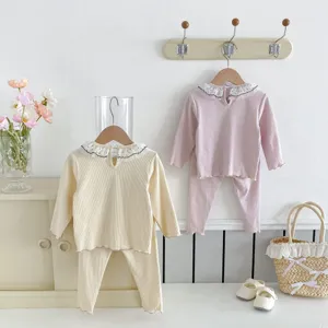 Detailed view of cute baby girl long sleeve ruffled collar top and leggings set in pastel tones.