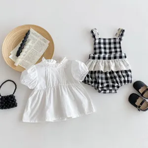 Detailed view of cute baby girl clothing set featuring white blouse and plaid romper outfit.