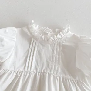 Detailed close-up shot of a white baby girl blouse featuring ruffles and short sleeves.