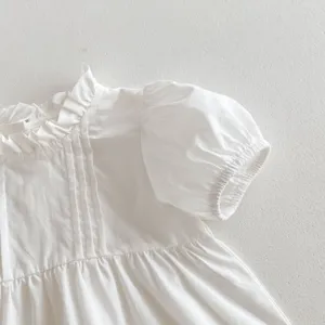 White baby girl blouse detail, cute short puff sleeves and delicate ruffles for summer.