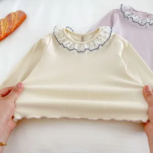 Close-up detail of infant baby ribbed long sleeve top with delicate lace ruffle collar and elasticity.