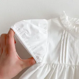Cute white baby girl blouse detail with ruffled collar and puff sleeves for summer casual.
