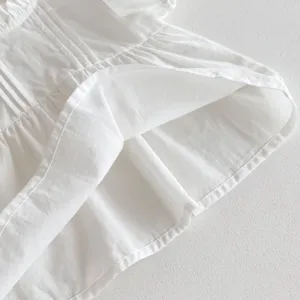 Close-up detail of infant white garment hem showing fine stitching and soft layered fabric texture.