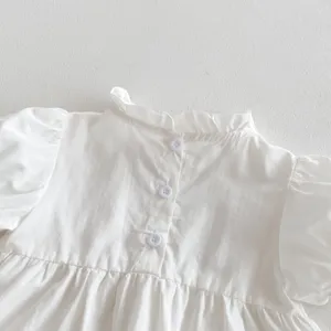 Close-up detail of infant white short-sleeve shirt back with delicate ruffles and buttons