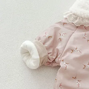 Close-up detail of baby winter jumpsuit with floral pattern, cozy fleece collar, ribbed cuffs.