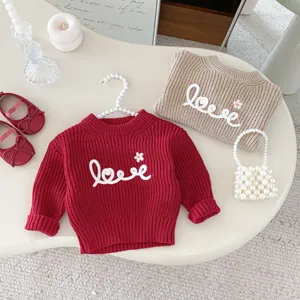 Detailed shot of kids knit sweater with letter embroidery and pearl bag accessory layout.