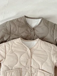 Nahaufnahme Detail der warmen, gesteppten Babymantel Winterjacke in zwei neutralen Tönen.