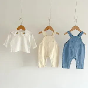 Cute baby clothing set featuring a white ruffled blouse and denim overalls for infants.