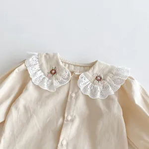 Exquisiter, spitzenbesetzter Bubikragen mit zarter Blumenstickerei im Detail der Babybluse.