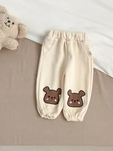 Gedetailleerd uitzicht op de schattige baby casual broek met berenborduurwerk zachte stof.
