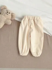 Detailopname van schattige baby ribfluwelen joggingbroek in crèmekleur met elastische boorden.
