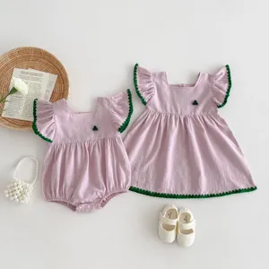 Baby girl summer pink romper dress set with green scalloped trim and sweet floral accent.