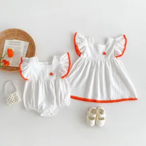 Detailed shot of baby girl summer white romper and dress with cute orange ruffle trims.