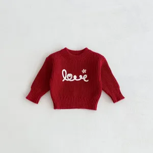 Detailed view of red knit baby sweater featuring cute white love embroidery and cozy texture.