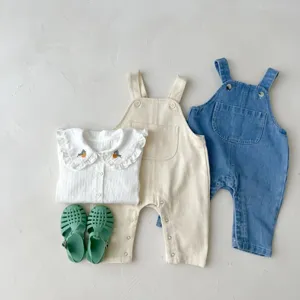 Detailed view of baby autumn outfit set, including ruffled blouse, overalls and jelly sandals.