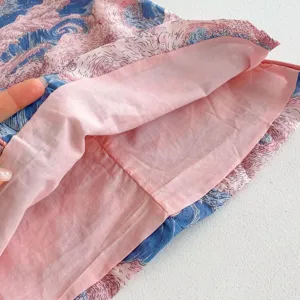 Close-up detail of girls summer dress inner lining, soft pink fabric and wave print texture.