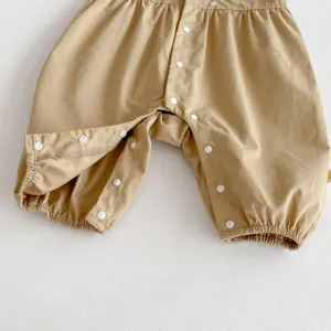 Detaillierte Nahaufnahme eines beigen Baby Rompers mit Druckknöpfen und elastischen Bündchen.