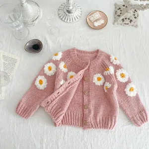 Detailed close-up of handmade daisy embroidered baby knit cardigan, soft pink texture style.